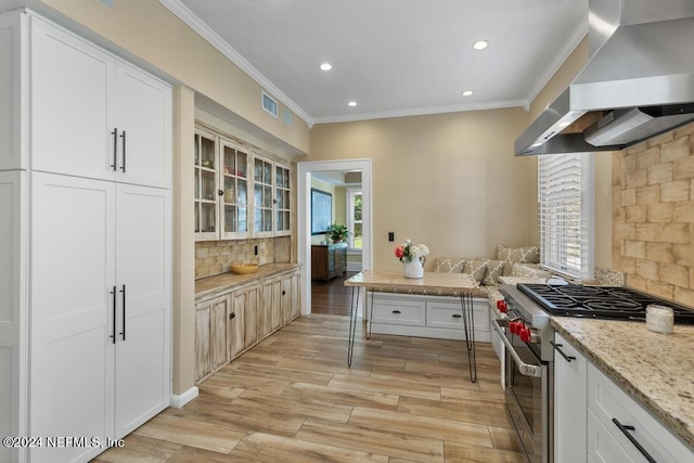 kitchen with white cabinets, light stone counters, high end stainless steel range, and wall chimney range hood