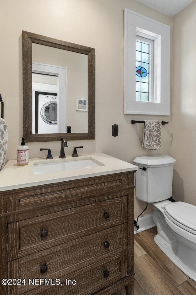 bathroom featuring hardwood / wood-style flooring, vanity, toilet, and washer / clothes dryer