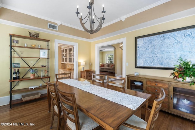 dining area with a notable chandelier, crown molding, and dark wood-type flooring