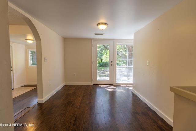 empty room featuring plenty of natural light and dark hardwood / wood-style flooring