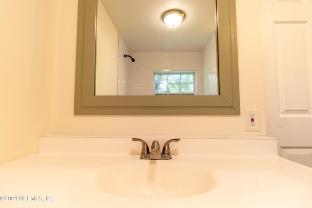 bathroom with tiled shower and vanity