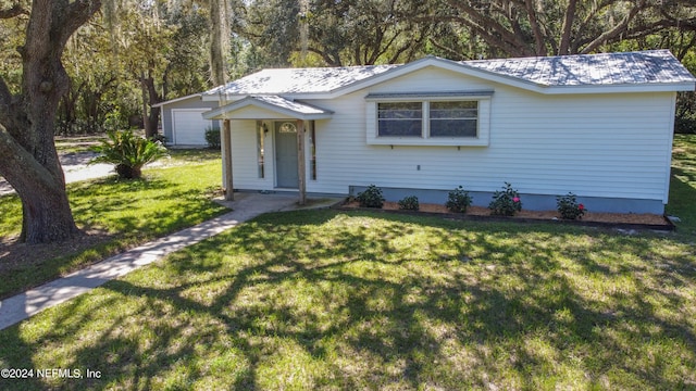 view of front of home with a front yard, a garage, and an outbuilding