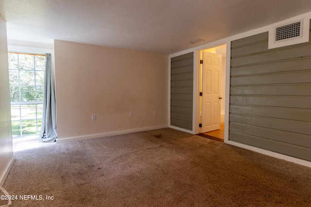 carpeted empty room featuring a textured ceiling