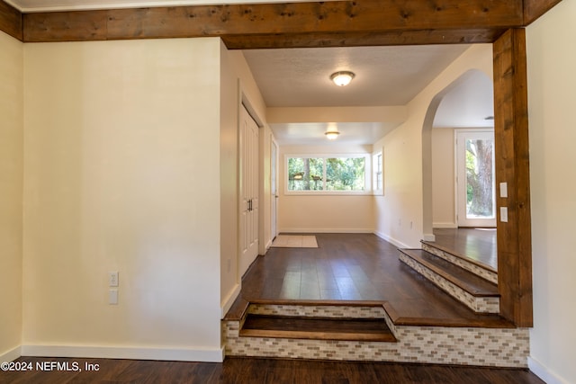 doorway to outside featuring dark hardwood / wood-style flooring and beamed ceiling