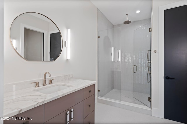 bathroom with a shower with shower door and vanity