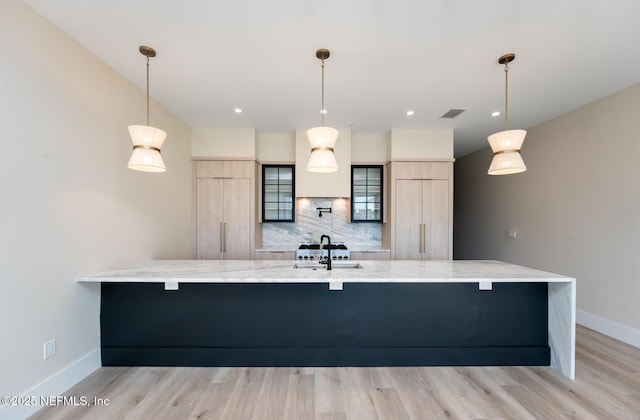 kitchen featuring sink, hanging light fixtures, light brown cabinets, and kitchen peninsula