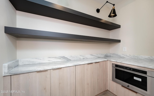 kitchen featuring light brown cabinets and light stone counters