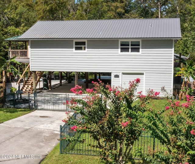 view of front facade featuring concrete driveway, stairway, fence, metal roof, and a carport