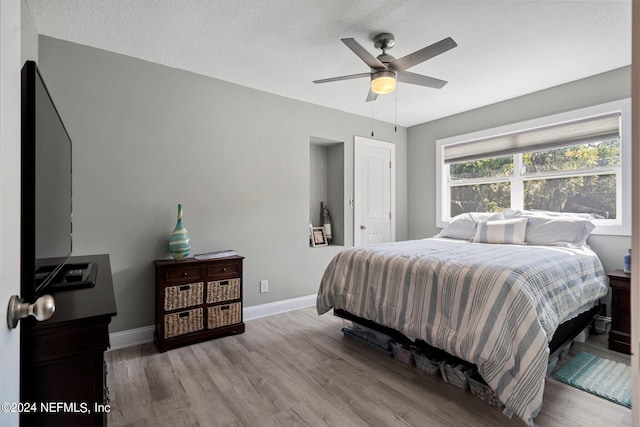 bedroom with ceiling fan, a textured ceiling, and light wood-type flooring