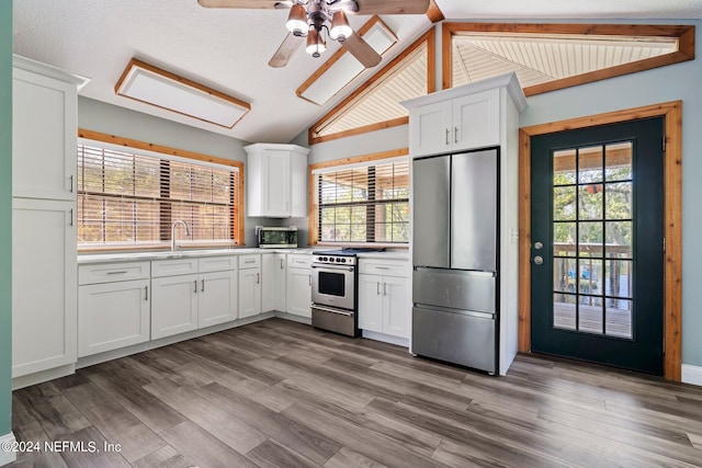 kitchen featuring light countertops, lofted ceiling, stainless steel appliances, white cabinets, and wood finished floors
