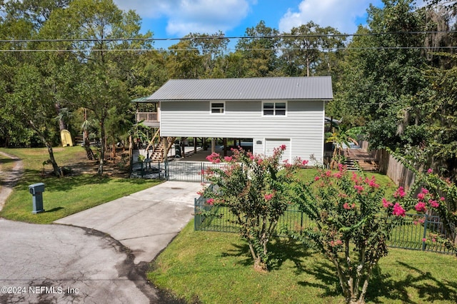 view of front of house with metal roof, stairs, a front yard, a fenced front yard, and driveway