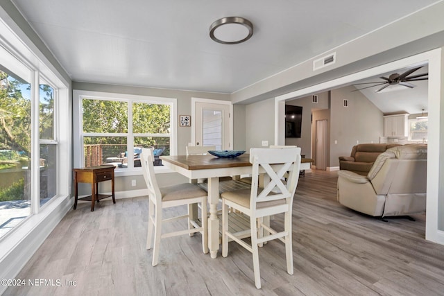 dining room with lofted ceiling, light wood-type flooring, baseboards, visible vents, and ceiling fan