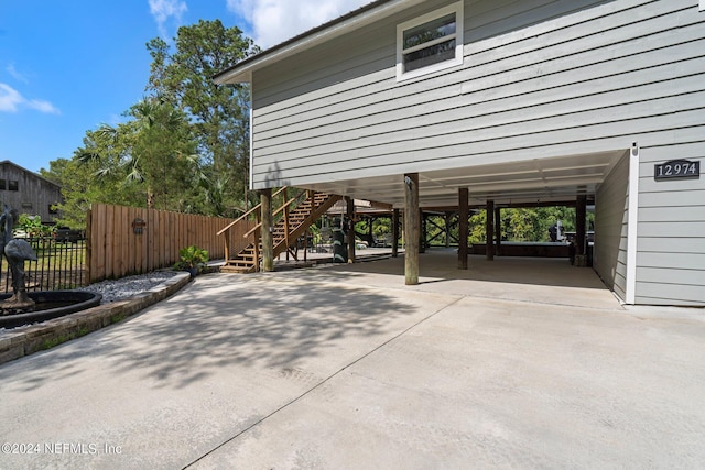 exterior space featuring driveway, a carport, fence, and stairway