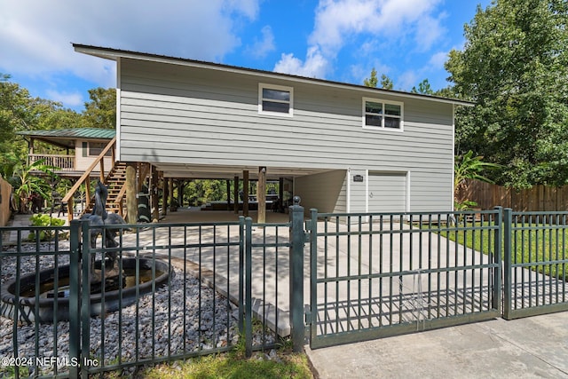 view of front of home featuring a gate, a carport, fence, and stairway