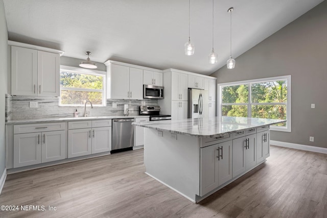 kitchen featuring pendant lighting, white cabinetry, backsplash, stainless steel appliances, and a kitchen island