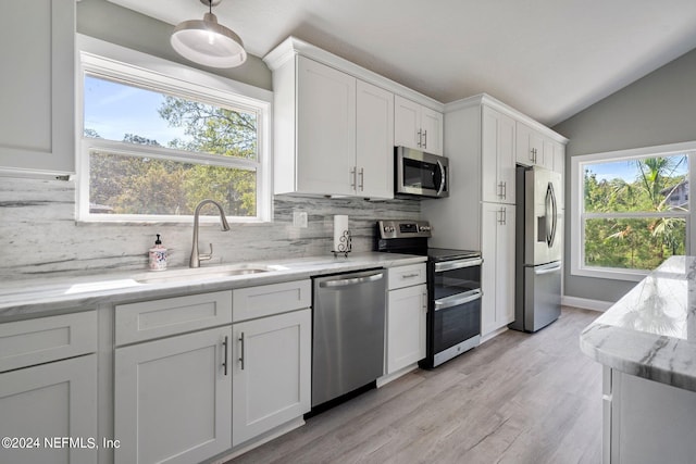 kitchen featuring sink, light stone counters, vaulted ceiling, stainless steel appliances, and white cabinets