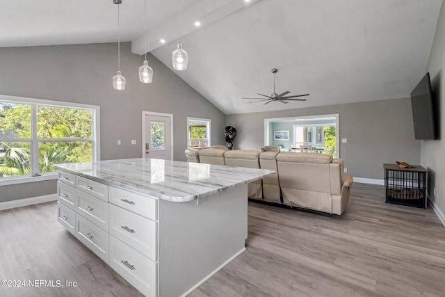 kitchen featuring white cabinetry, decorative light fixtures, light wood-type flooring, a kitchen island, and a healthy amount of sunlight