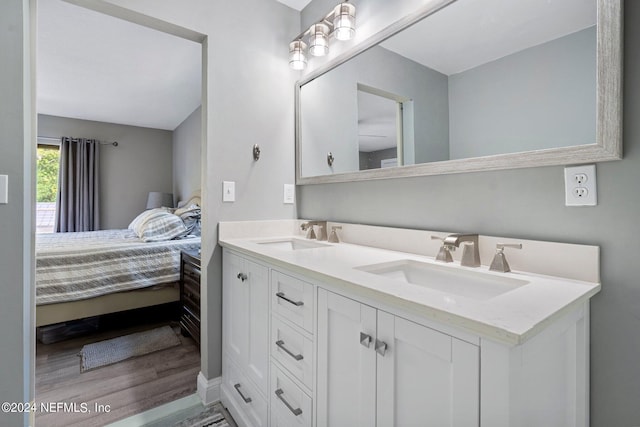 bathroom with double vanity, a sink, ensuite bathroom, and wood finished floors