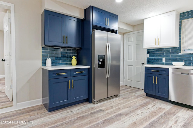 kitchen featuring light wood finished floors, light countertops, appliances with stainless steel finishes, and blue cabinetry
