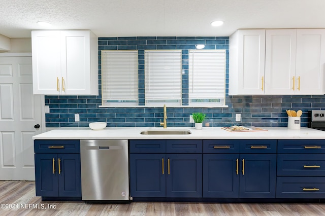 kitchen with stainless steel dishwasher, light countertops, a sink, and blue cabinetry