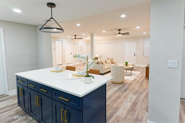 kitchen featuring light wood-type flooring, blue cabinets, a center island, and decorative light fixtures