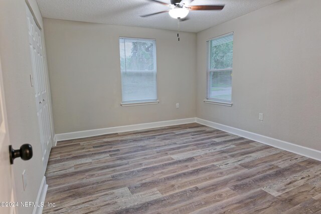 empty room with ceiling fan, a textured ceiling, and light hardwood / wood-style flooring