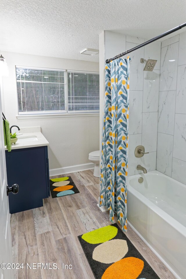 full bathroom featuring vanity, shower / bath combination with curtain, a textured ceiling, wood-type flooring, and toilet