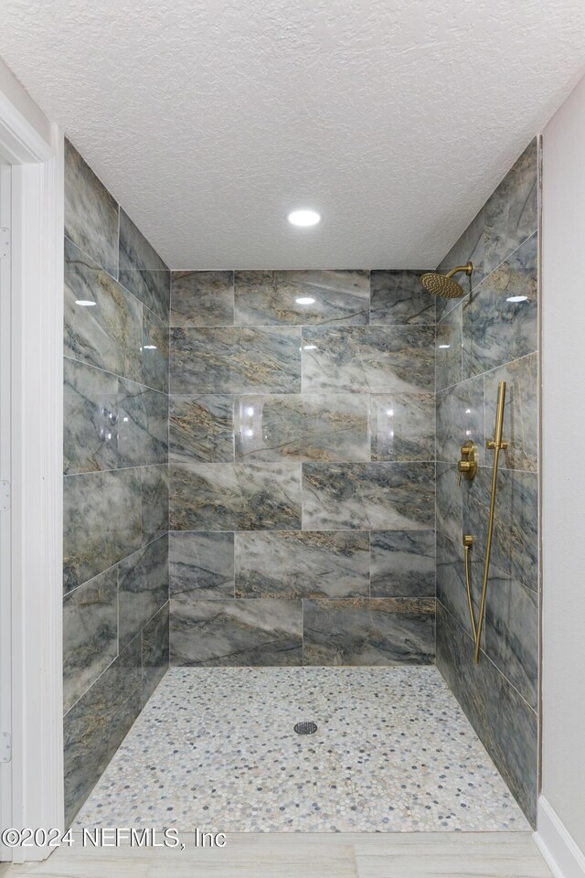 bathroom featuring a textured ceiling and tiled shower