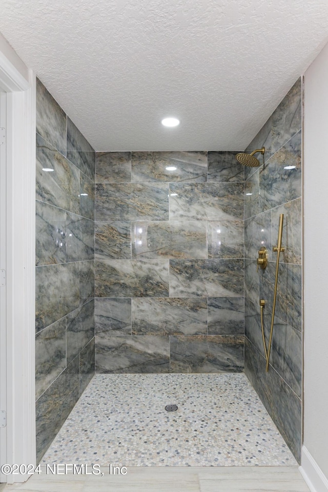 bathroom featuring a tile shower and a textured ceiling