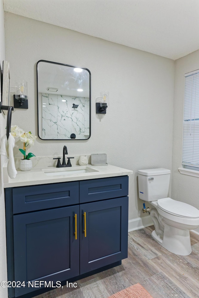 full bathroom with toilet, a shower, vanity, wood finished floors, and baseboards