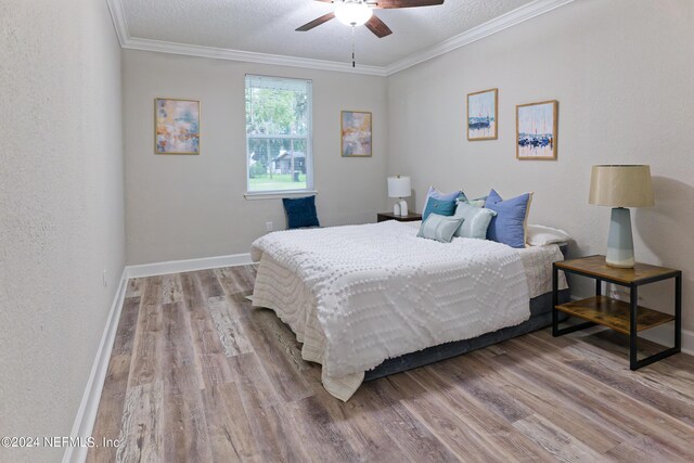 bedroom featuring a textured ceiling, light hardwood / wood-style floors, ceiling fan, and crown molding