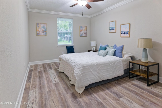 bedroom with baseboards, a textured ceiling, wood finished floors, and crown molding