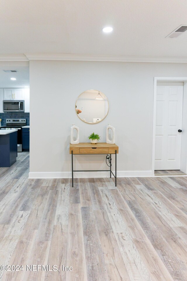 hallway featuring light hardwood / wood-style floors and ornamental molding