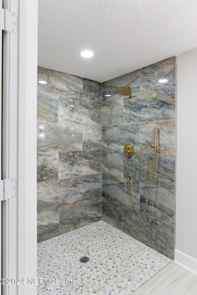 bathroom with wood-type flooring, a textured ceiling, and tiled shower