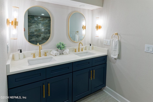 bathroom with a textured wall, double vanity, and a sink