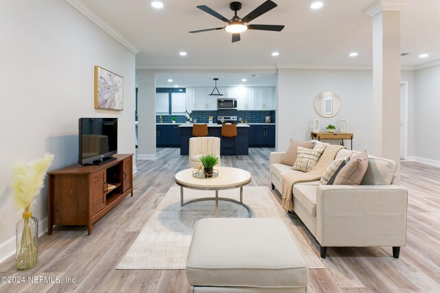 living room featuring ornamental molding, light wood-type flooring, and ceiling fan