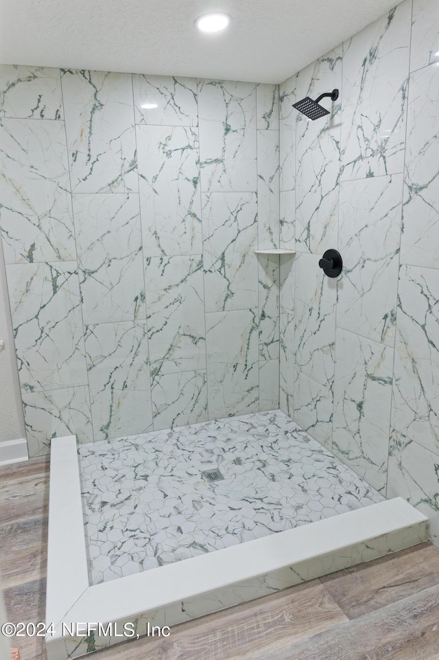 full bath featuring a tile shower and wood finished floors