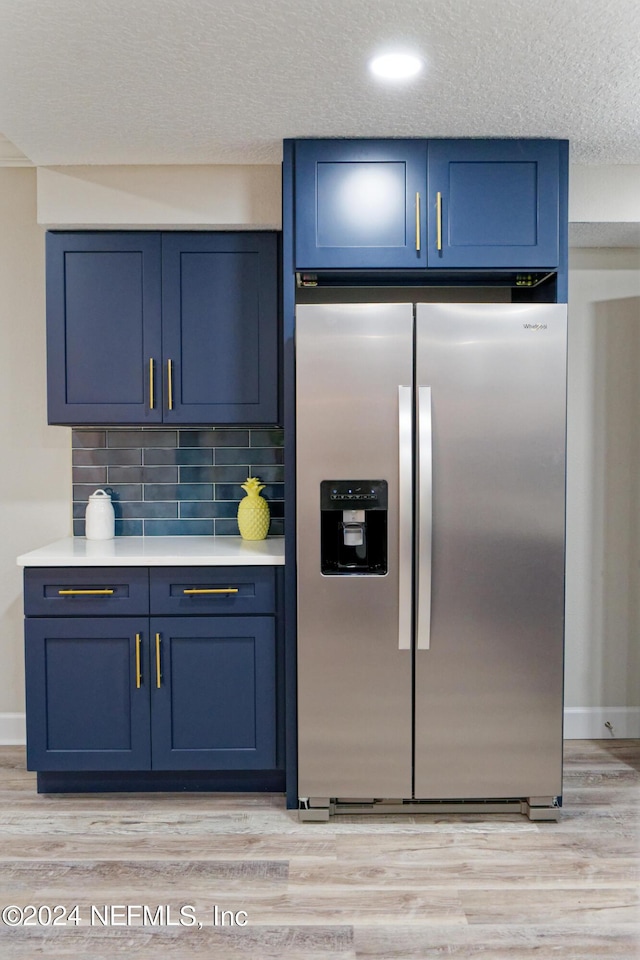 kitchen with stainless steel fridge, blue cabinets, and light wood-style floors