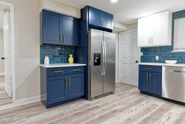 kitchen with a textured ceiling, backsplash, light hardwood / wood-style floors, and stainless steel appliances