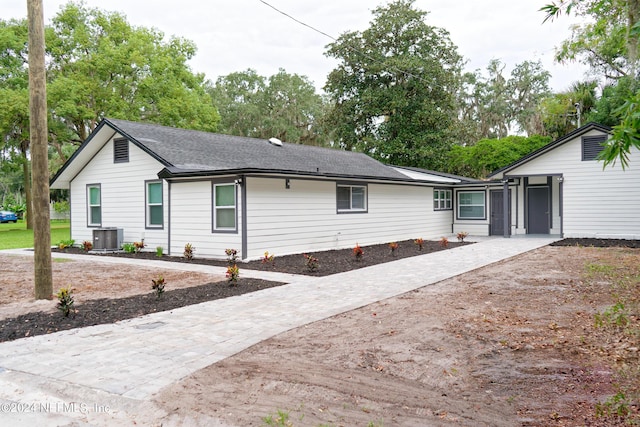 exterior space with driveway, a shingled roof, and central AC unit
