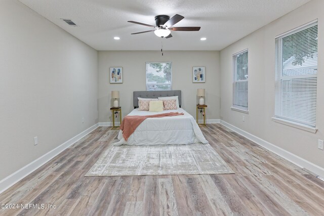 bedroom featuring a textured ceiling, light hardwood / wood-style floors, and ceiling fan