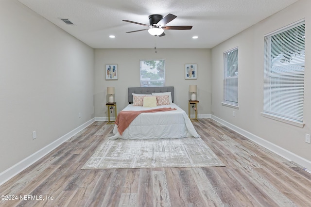 bedroom featuring a textured ceiling, visible vents, baseboards, wood finished floors, and recessed lighting