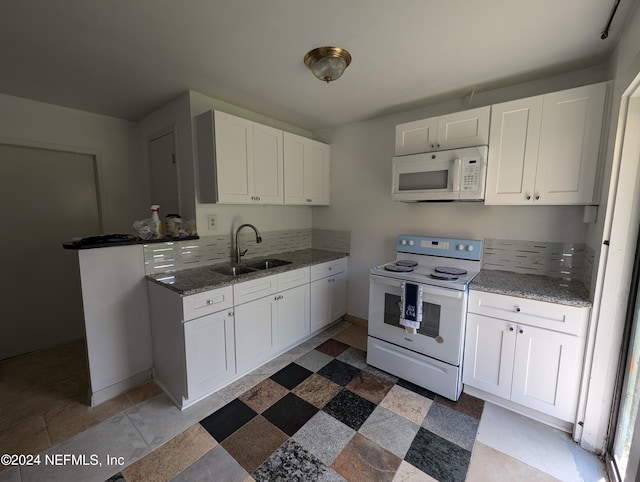 kitchen with dark stone countertops, sink, white appliances, and white cabinetry