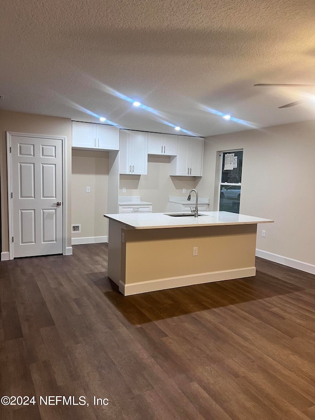 kitchen featuring a kitchen island with sink, sink, and white cabinets