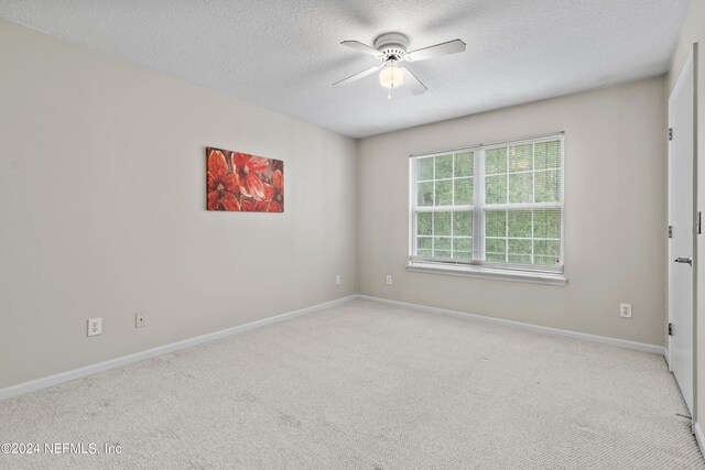 spare room featuring light carpet, a textured ceiling, and ceiling fan