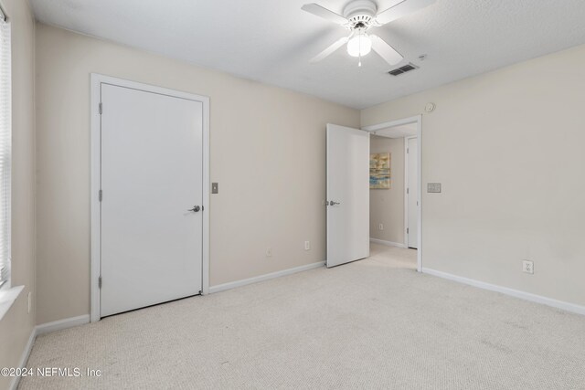 unfurnished bedroom with light colored carpet and ceiling fan