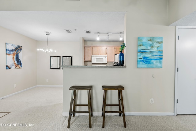 kitchen featuring light brown cabinetry, a notable chandelier, hanging light fixtures, and light carpet