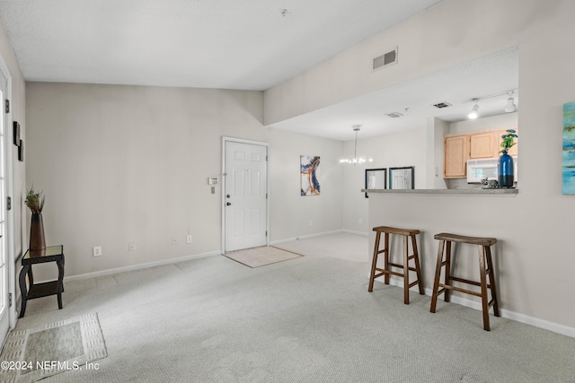 interior space with light colored carpet, a chandelier, and rail lighting