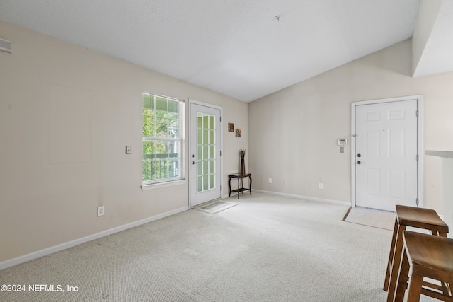 carpeted empty room with vaulted ceiling