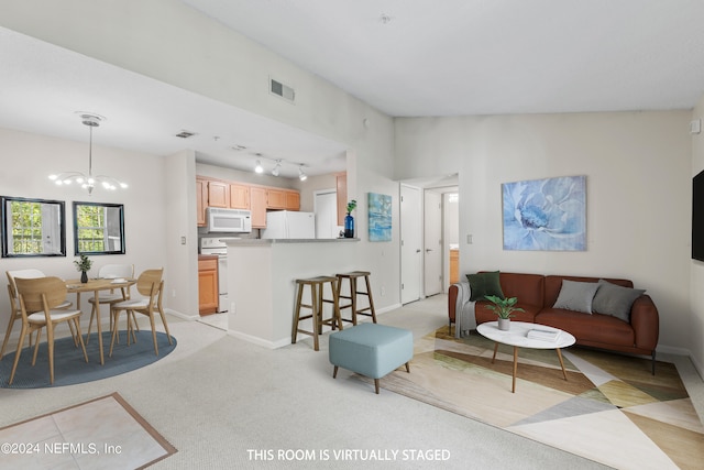 living room featuring track lighting, a notable chandelier, and light carpet